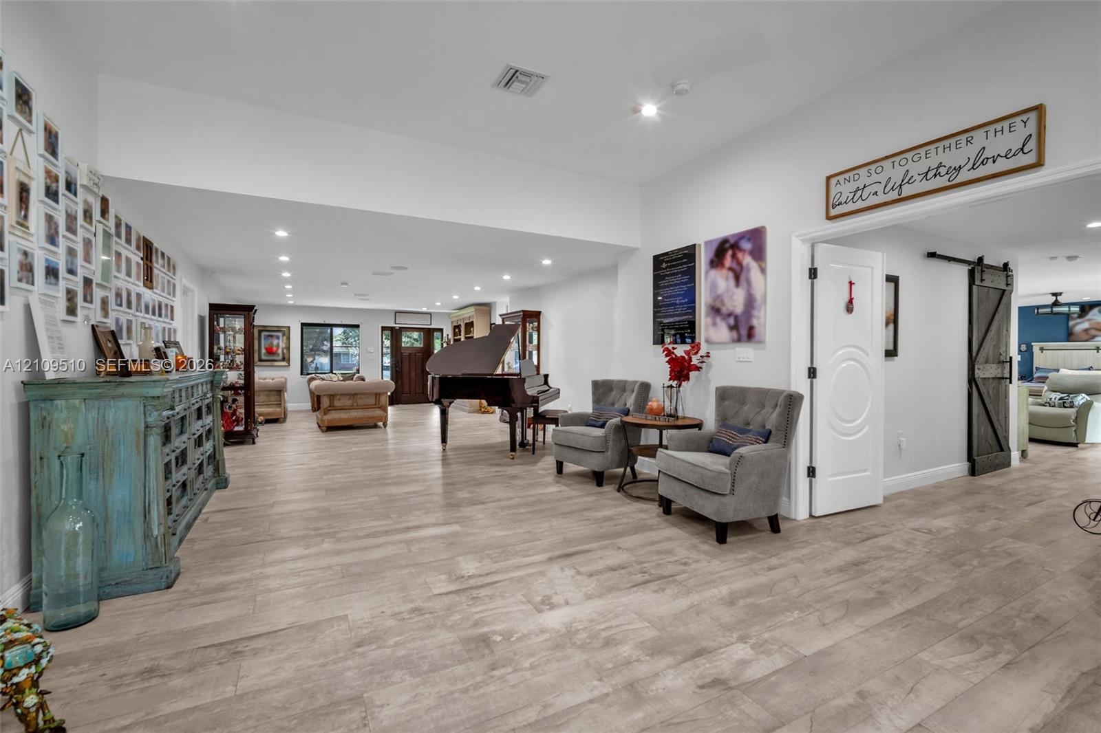 Open interior featuring wood-finish flooring, recessed lighting, and a sliding barn door with matte black hardware