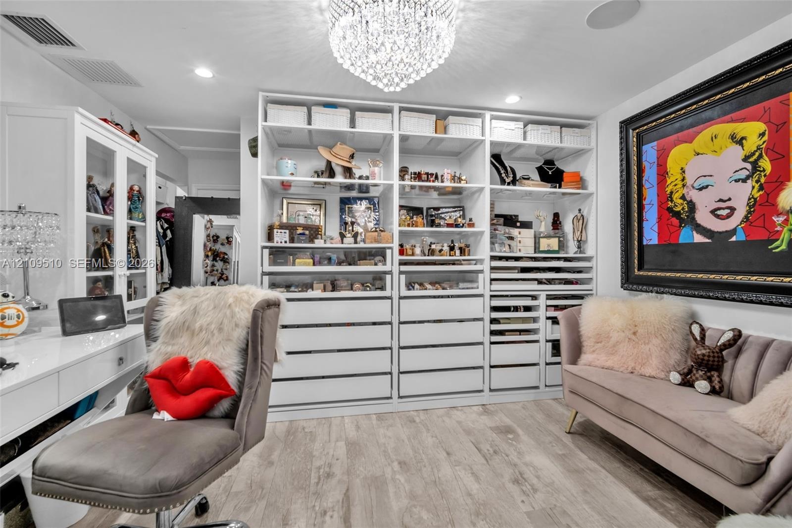 Custom built-in white cabinetry featuring extensive shelving, drawer storage, and glass-front display sections, complemented by wood-finish flooring a