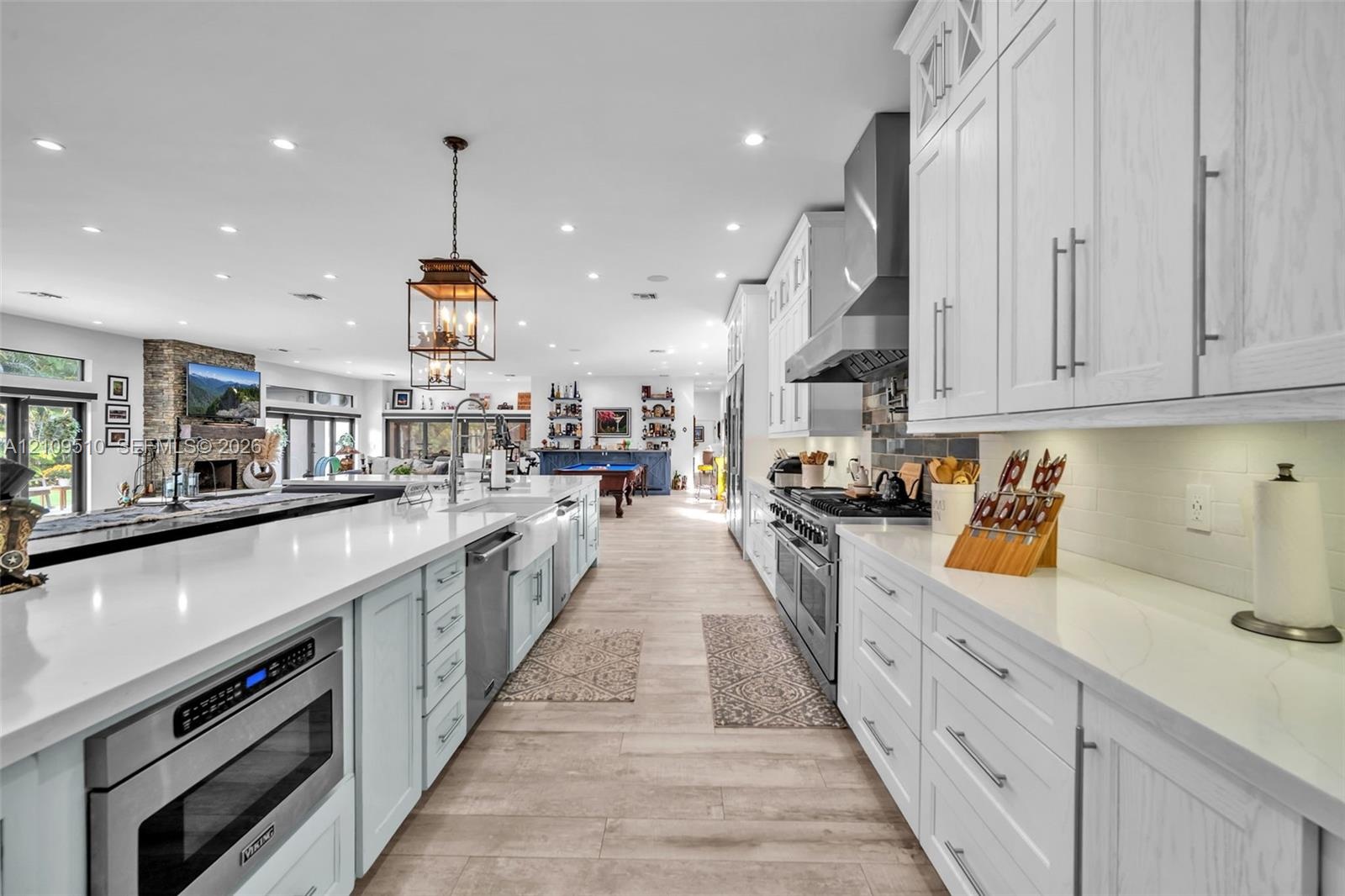 Kitchen featuring floor-to-ceiling white cabinetry, quartz countertops, a professional-grade stainless steel range with a matching hood, a farmhouse-s