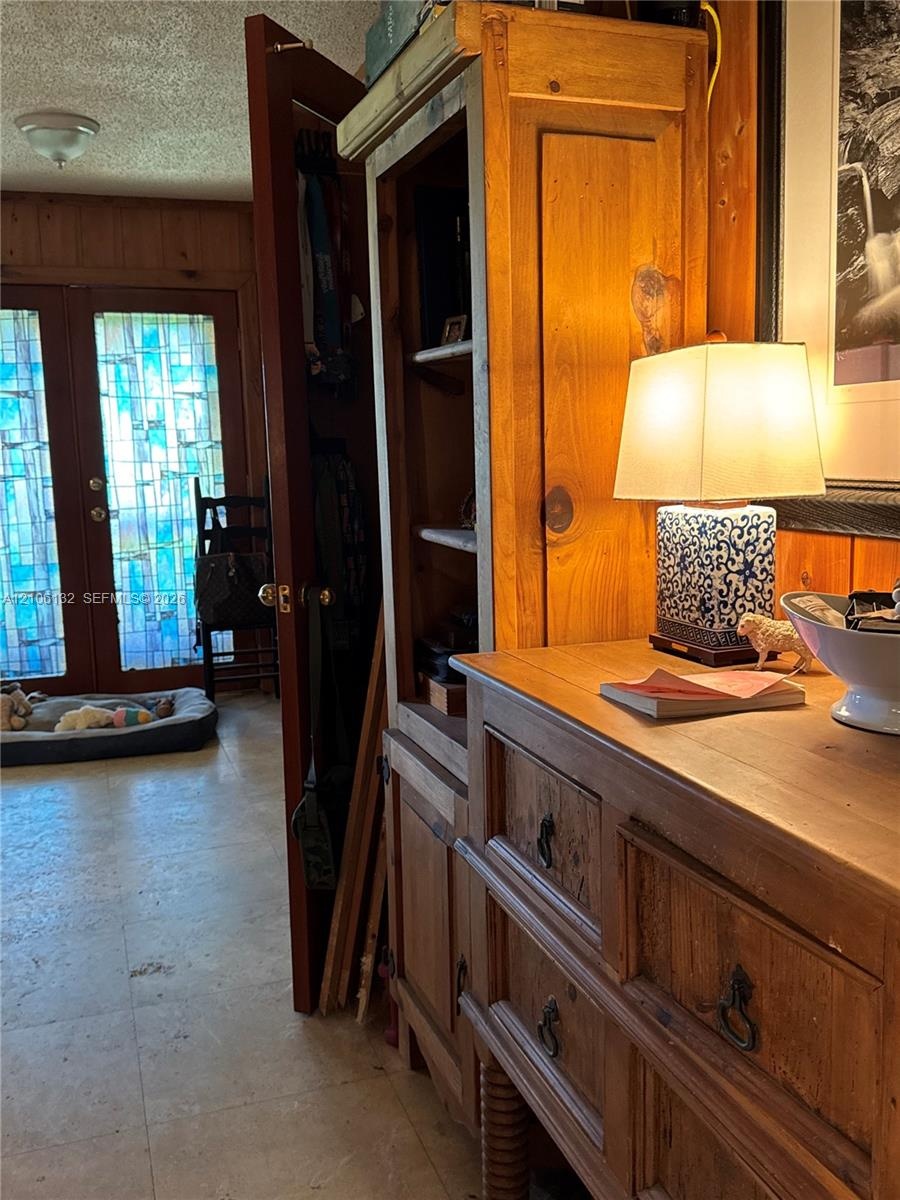 Double doors featuring stained glass inserts, wood-paneled walls, and built-in wood cabinetry