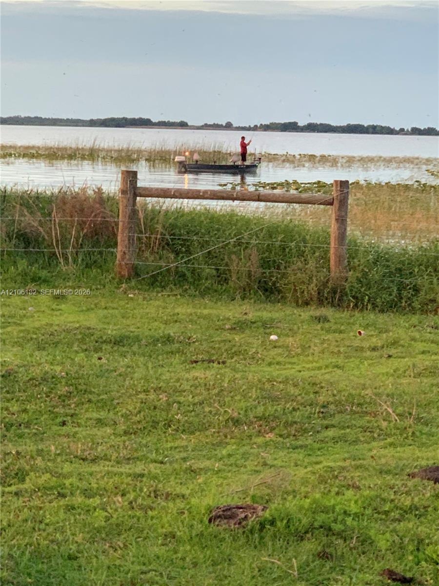 Waterfront acreage featuring natural shoreline vegetation and a post-and-wire perimeter fence