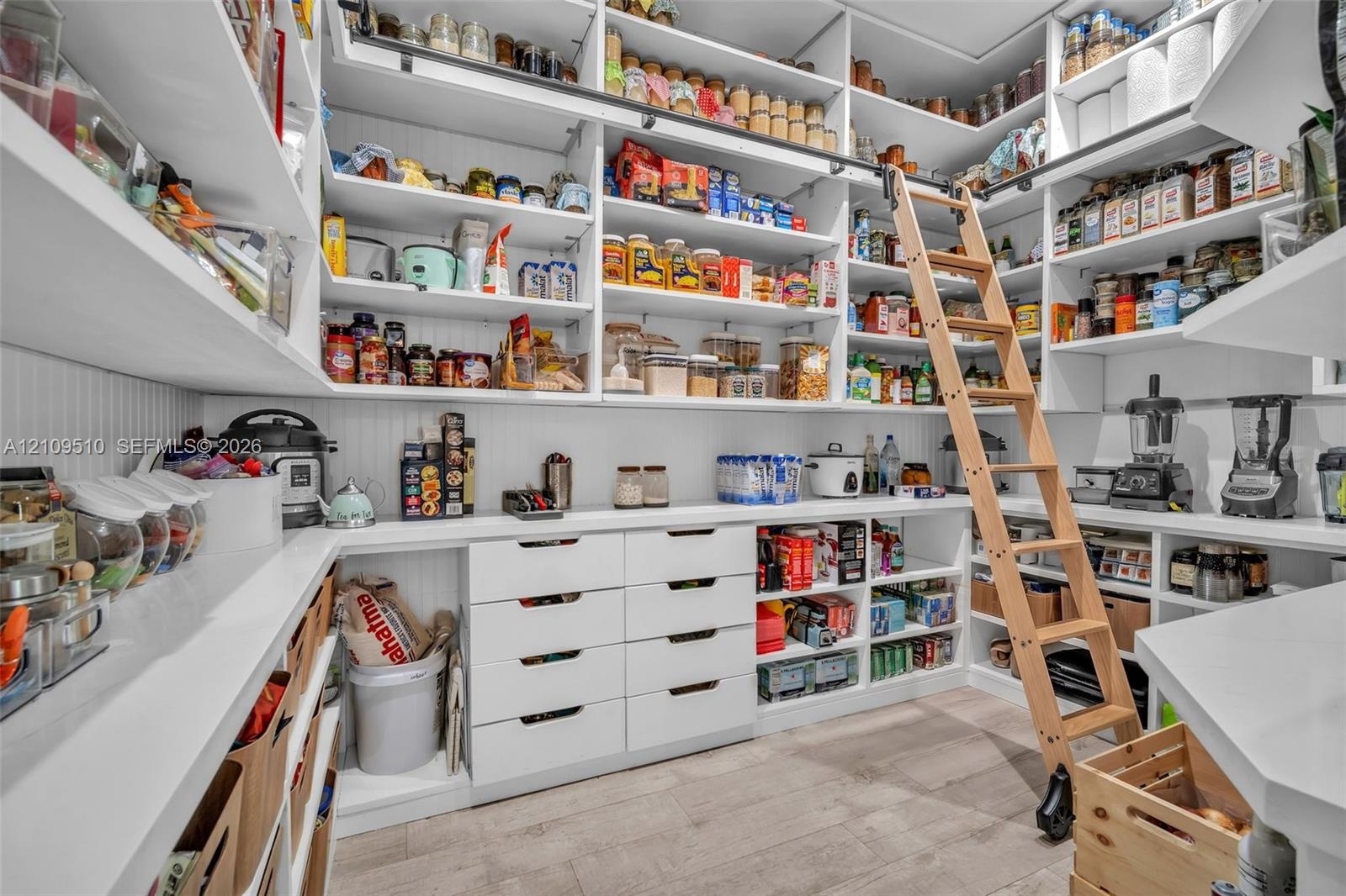 Custom walk-in pantry featuring expansive wall-to-wall shelving, floor-to-ceiling built-in cabinetry with integrated drawers, rolling library-style la