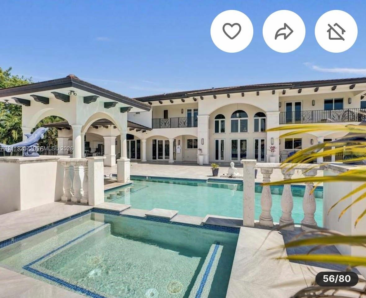 Two-story estate exterior featuring a tiled swimming pool with an integrated spa, stone balustrade railings, a covered patio with decorative support b