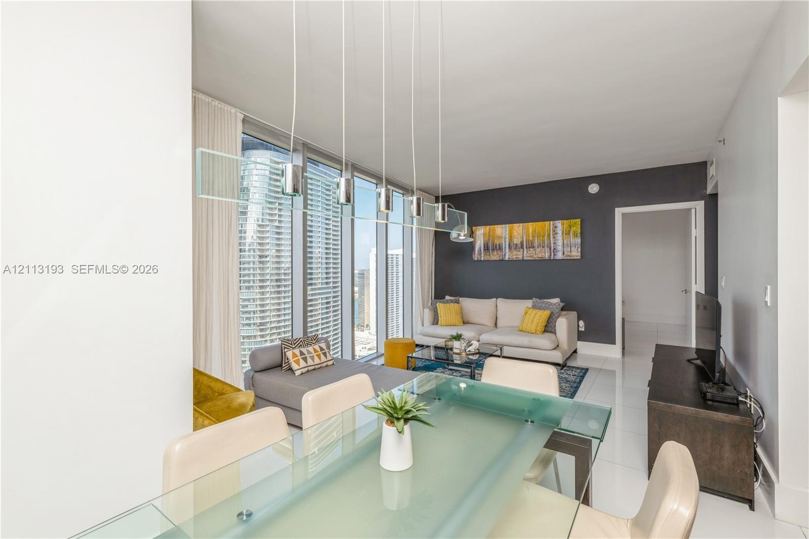 Floor-to-ceiling windows, polished tile flooring, contemporary multi-pendant lighting fixture, and a bold accent wall