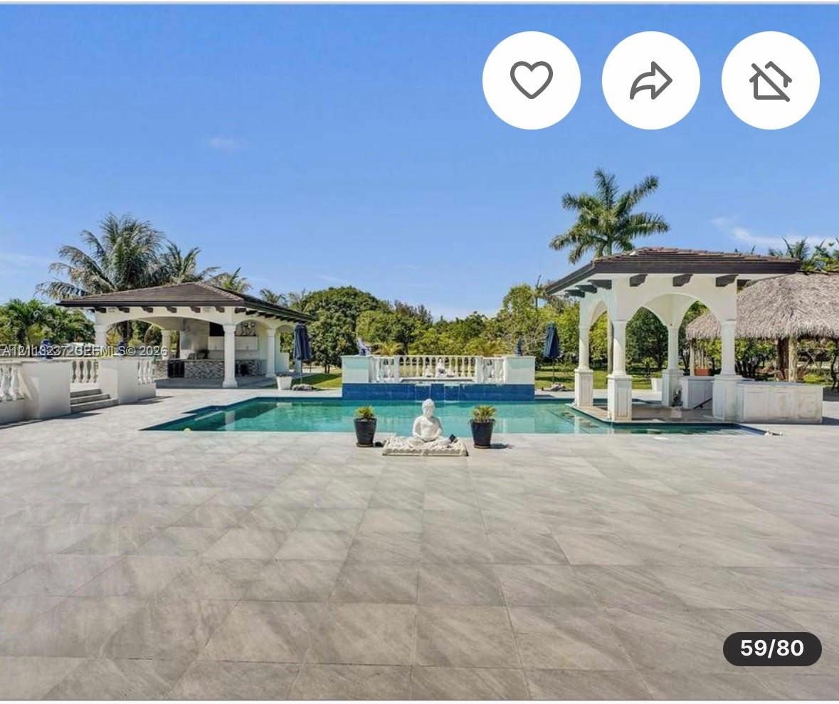 Extensive patio area with large-format tile flooring, rectangular pool, dual covered structures with architectural columns, and a tiered fountain feat