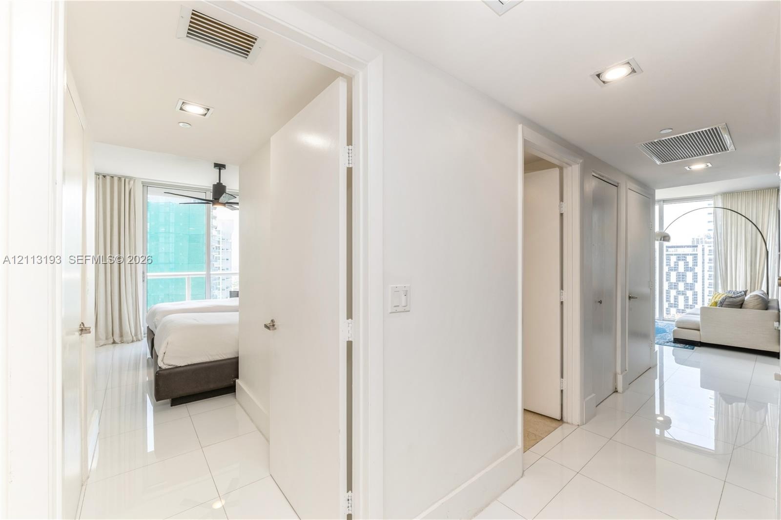 Glossy tile flooring, recessed ceiling lighting, and multiple interior passage doors