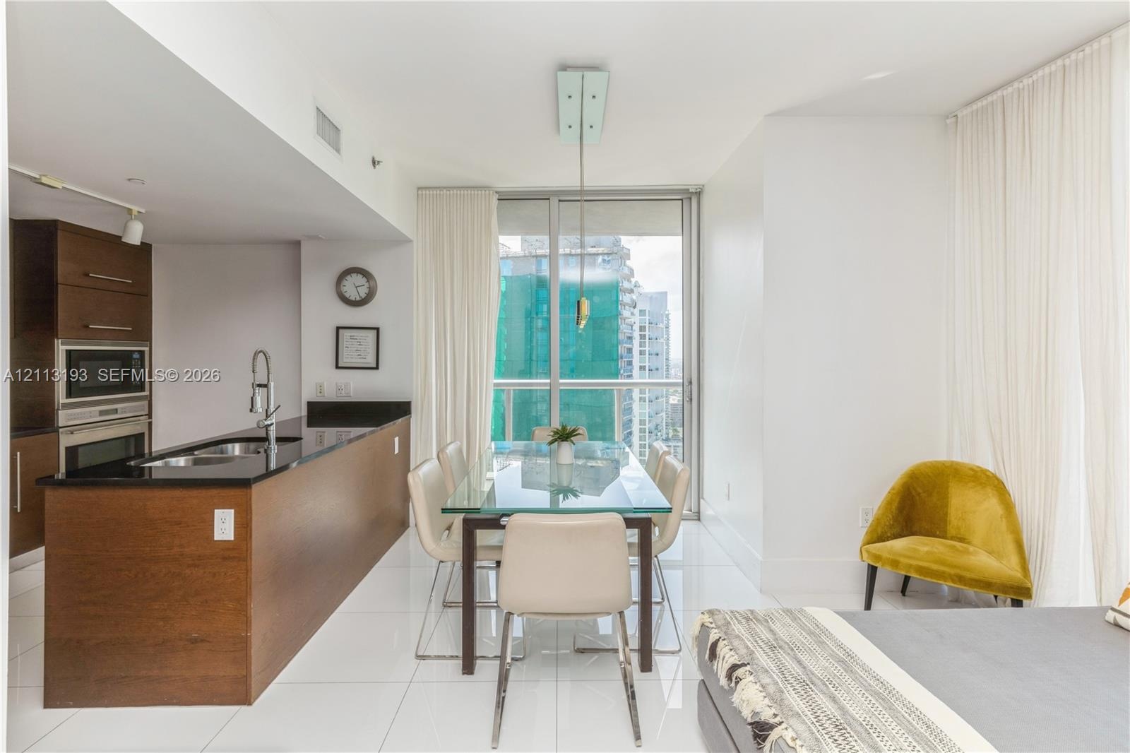 Kitchen featuring dark wood-finish cabinetry, black stone countertops, and built-in stainless steel appliances, paired with high-gloss tile flooring a