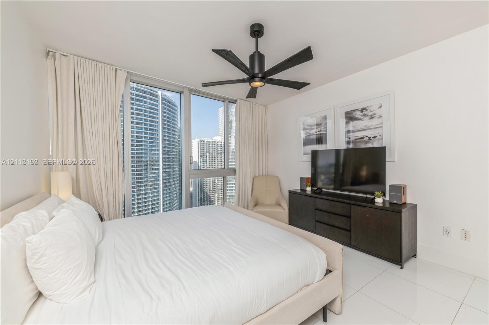 Floor-to-ceiling windows, polished white tile flooring, and a contemporary matte black ceiling fan