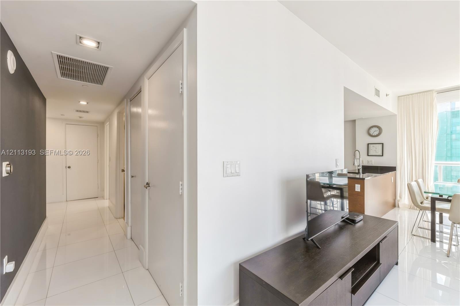 Interior hallway featuring polished tile flooring, recessed ceiling lighting, and contrasting dark-toned accent wall