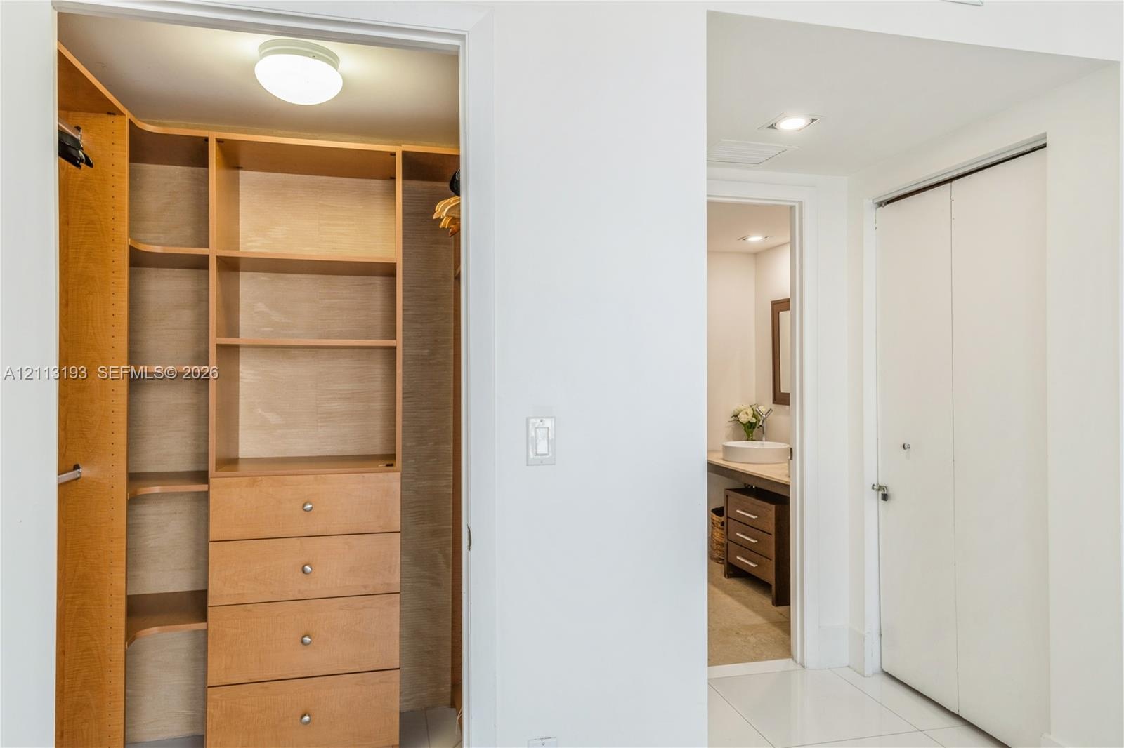 Custom built-in wood-finish shelving and drawer storage with overhead flush-mount lighting