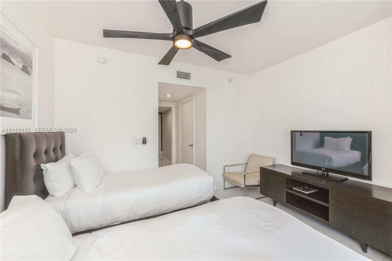 Four-blade matte black ceiling fan with integrated lighting and smooth white wall finish