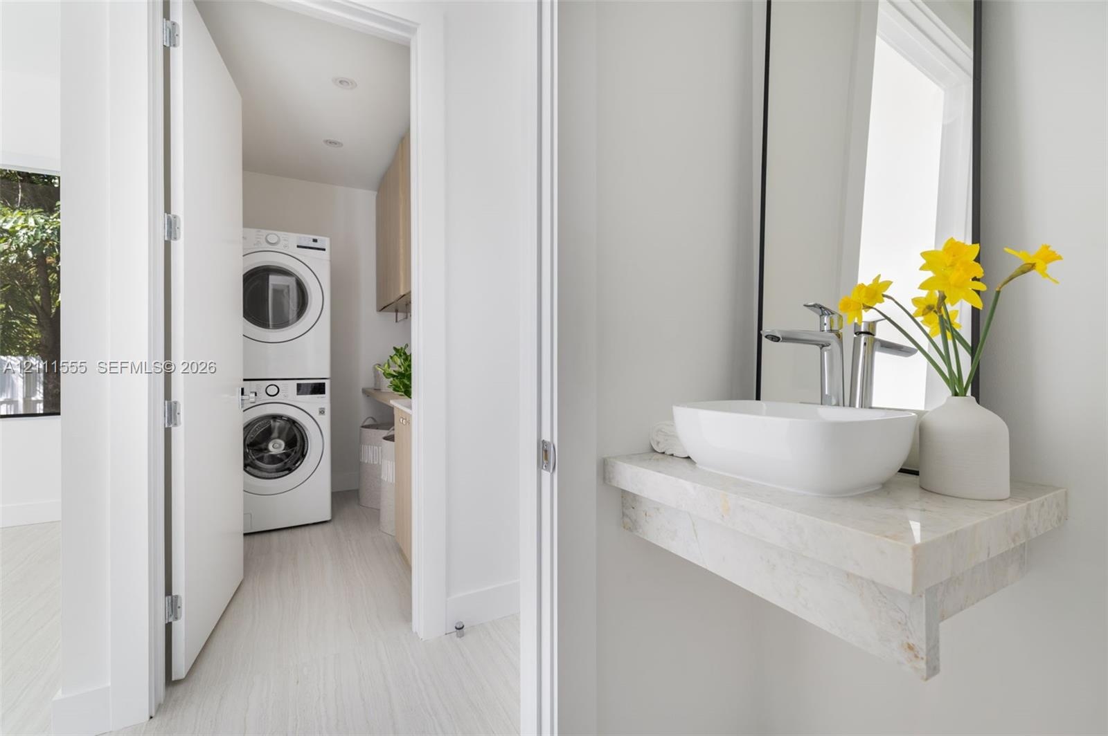 Floating stone vanity with vessel sink and metal faucet, paired with a laundry area featuring a stacked washer and dryer set and custom cabinetry