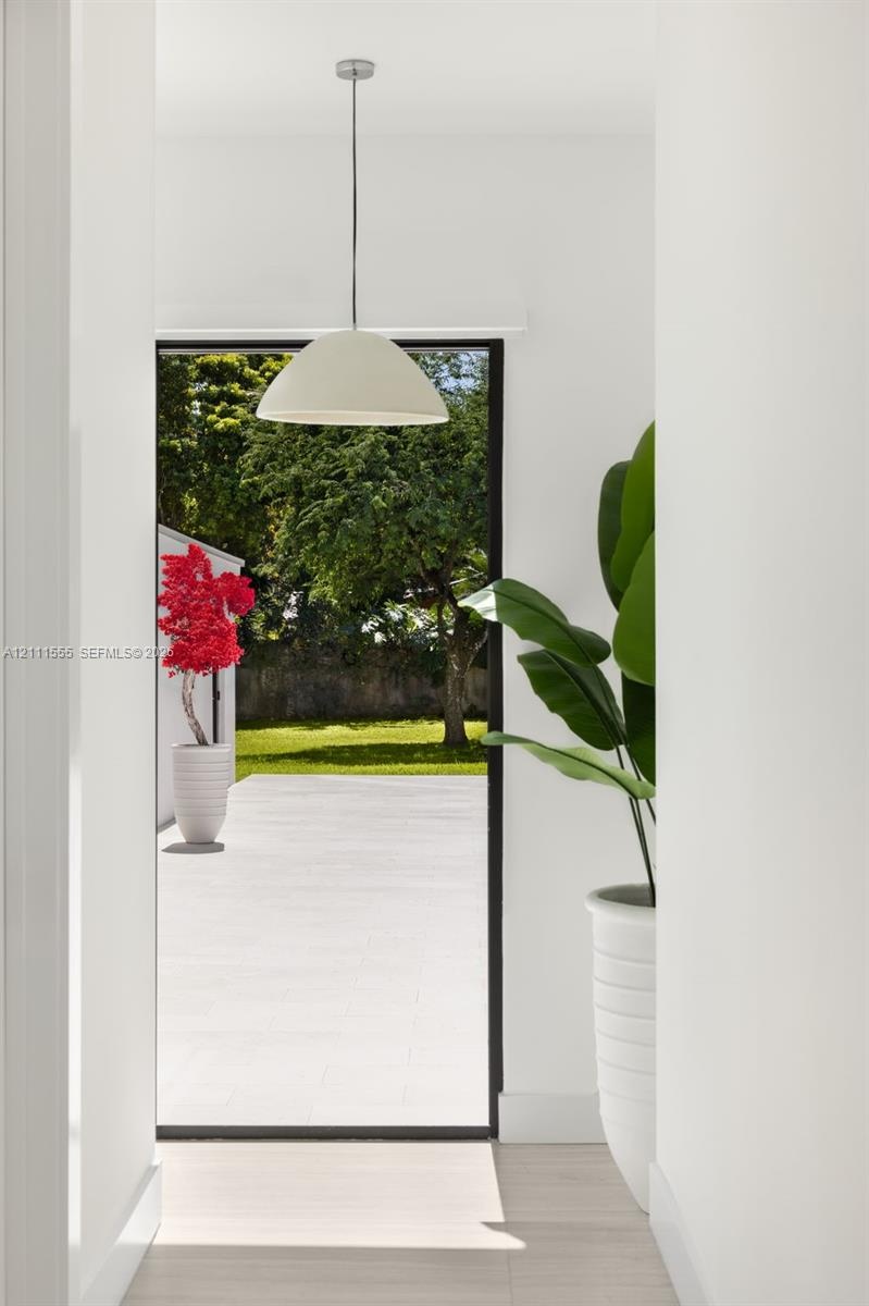 Minimalist pendant lighting, wide-format glass door, and exterior stone patio