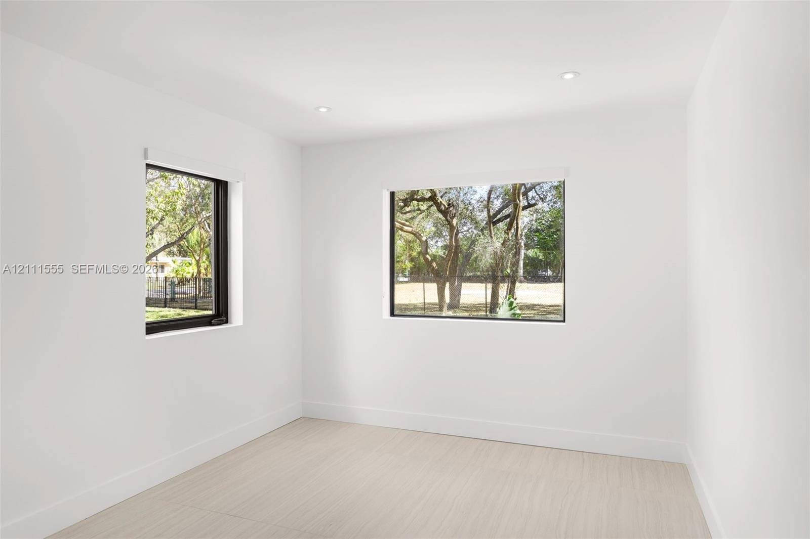 Bright interior space featuring neutral walls, light wood-finish flooring, recessed lighting, and large windows with black frames