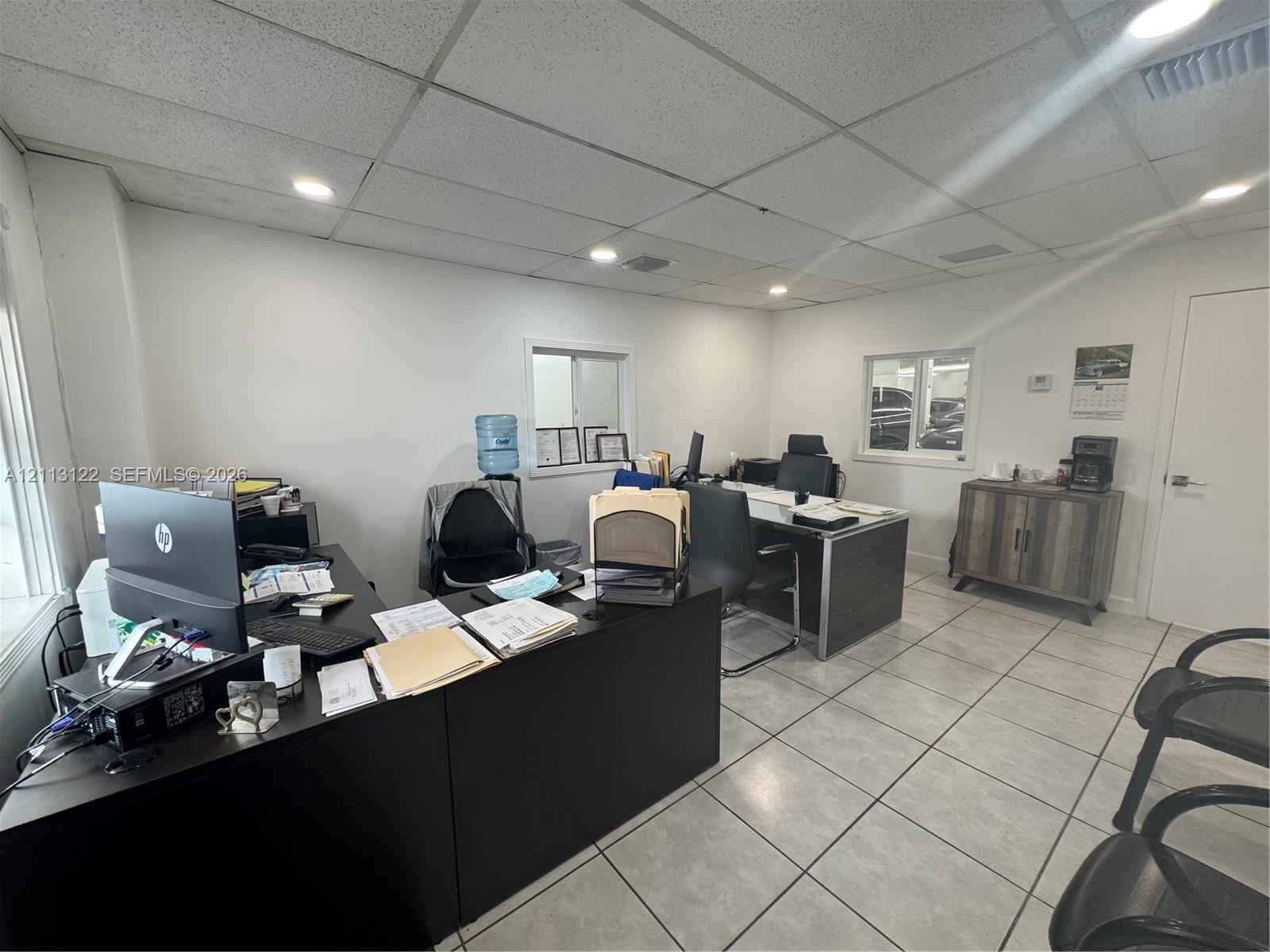 Interior room featuring recessed ceiling lighting, grid-pattern ceiling tiles, and large-format ceramic floor tile