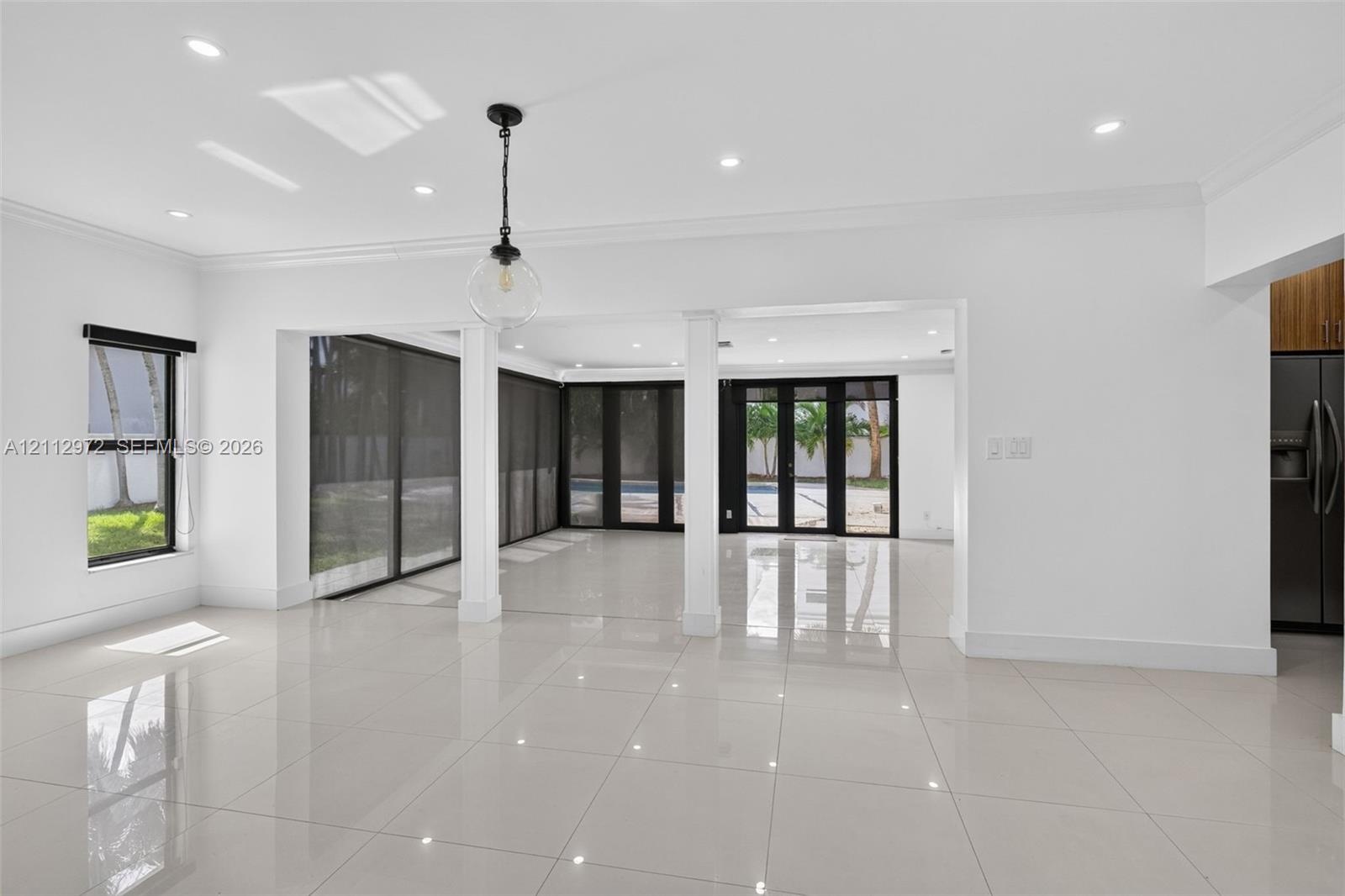Large-format polished tile flooring, recessed ceiling lighting, structural support columns, black-framed sliding glass doors, and a decorative globe p
