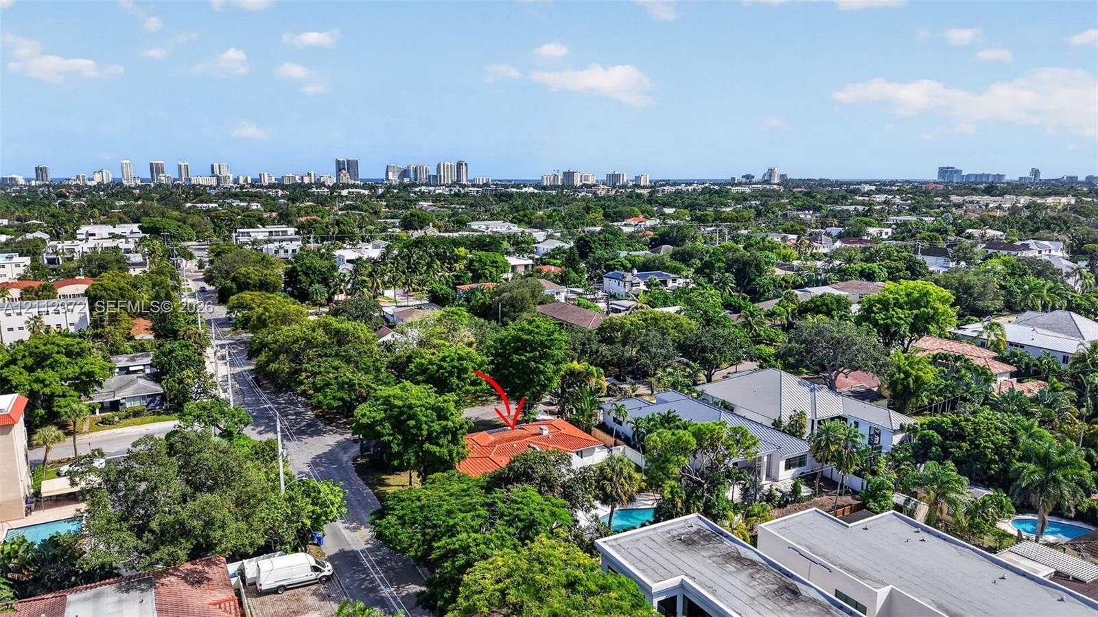 Aerial perspective of a residential property featuring a clay tile roof and dense mature tree canopy