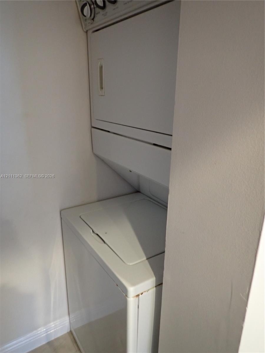 Stacked white laundry appliance unit situated within a recessed utility closet