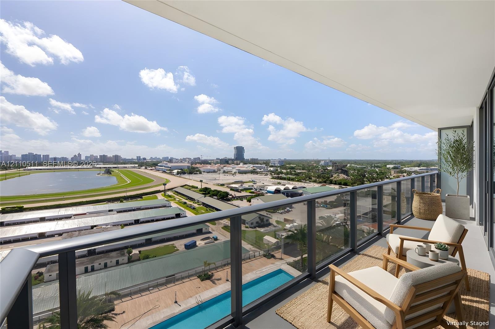 Covered terrace featuring a glass panel railing, expansive exterior area, and direct exposure to race track and urban scenery