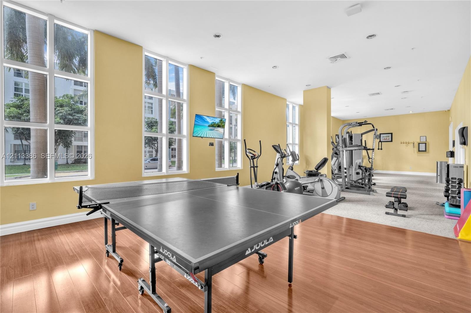 Fitness center featuring floor-to-ceiling windows, wood-finish flooring, and recessed ceiling lighting