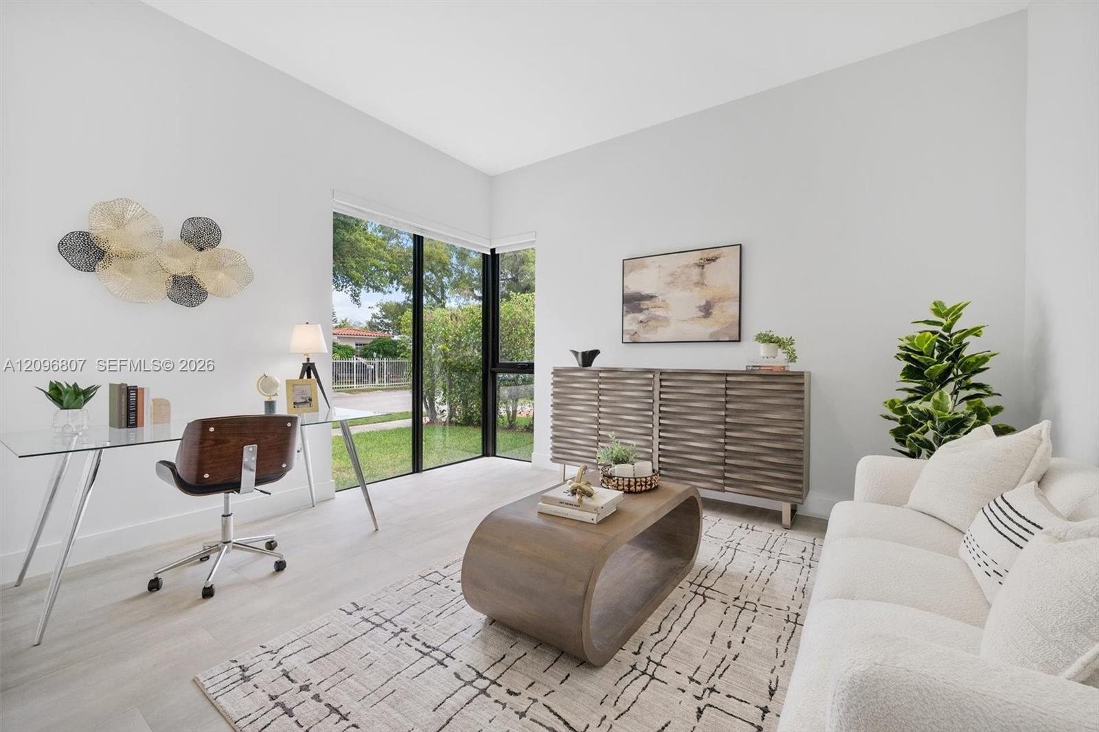 Neutral interior space featuring high ceilings, wood-finish flooring, and floor-to-ceiling corner windows with black frames