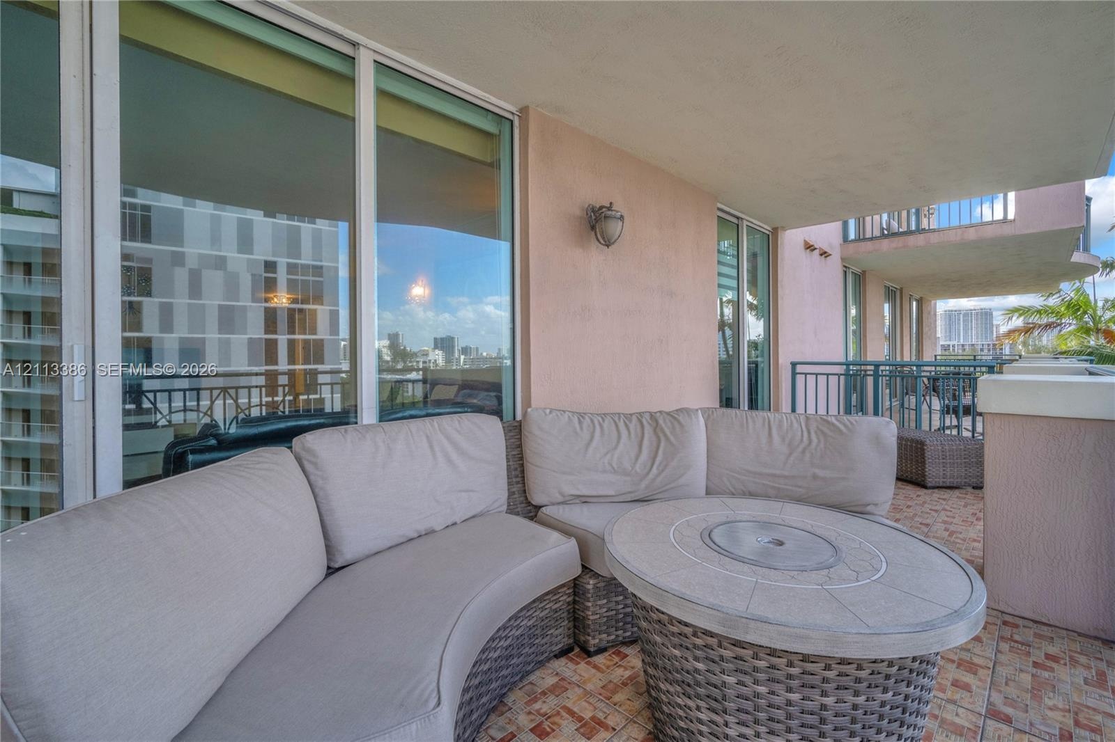 Covered balcony featuring floor-to-ceiling glass sliding doors, stone-tiled flooring, and metal railing