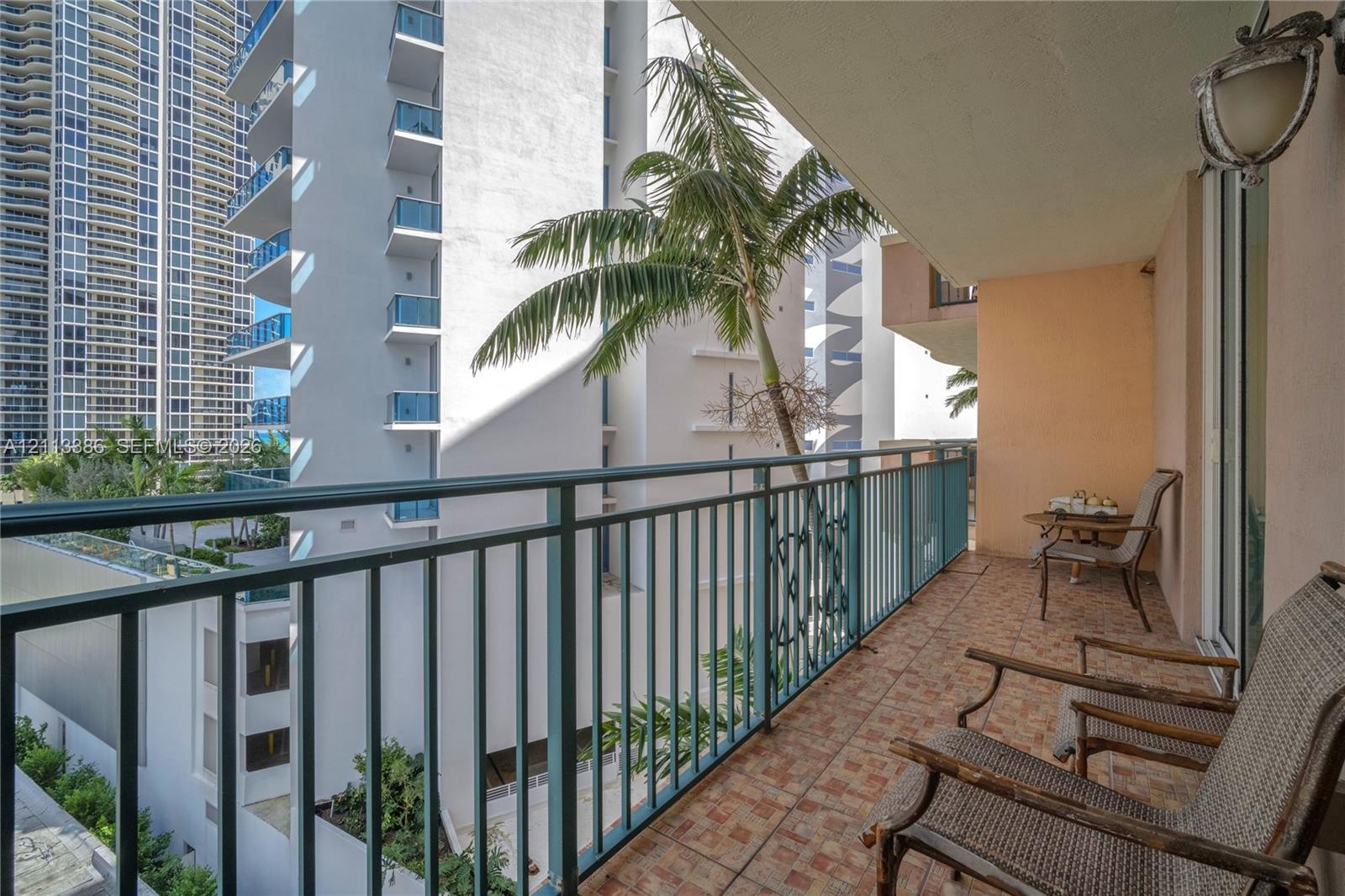 Private balcony featuring tiled flooring, a metal railing, and a wall-mounted light fixture