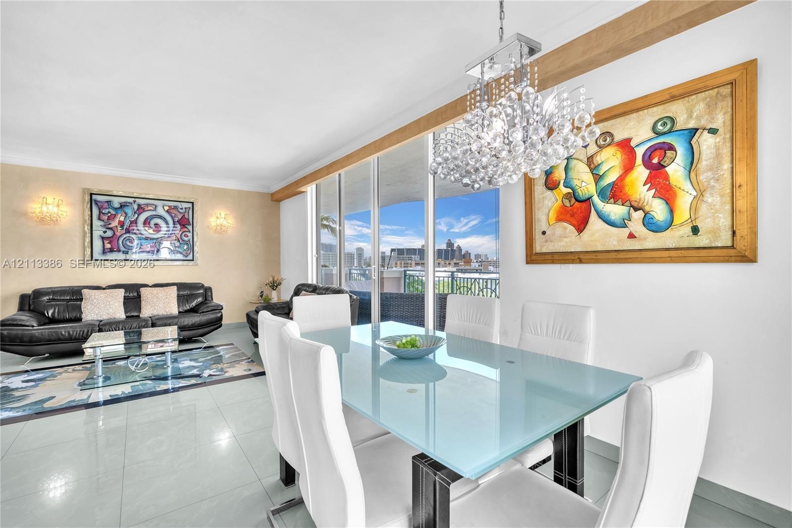 Floor-to-ceiling glass sliding doors, crystalline multi-tiered chandelier, neutral large-format tile flooring, and integrated wall sconces