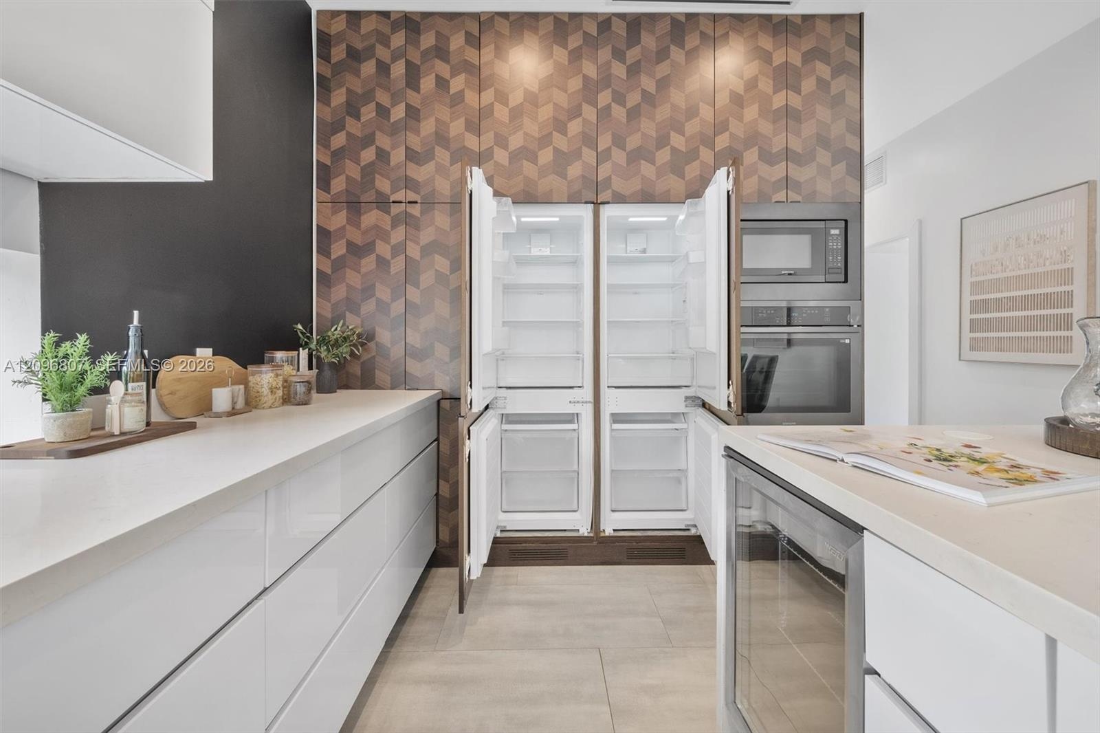 Modern kitchen featuring full-height geometric patterned cabinetry, integrated side-by-side refrigerator, built-in stainless steel oven and microwave,