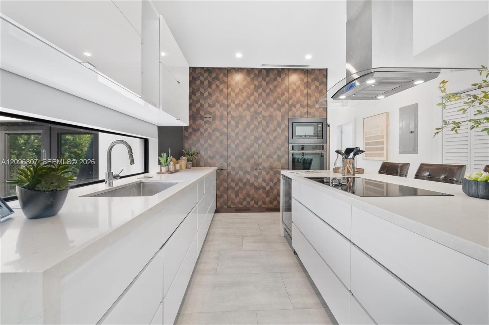 Modern kitchen featuring flat-panel white cabinetry, expansive stone countertops, geometric-patterned wall paneling, built-in stainless steel applianc