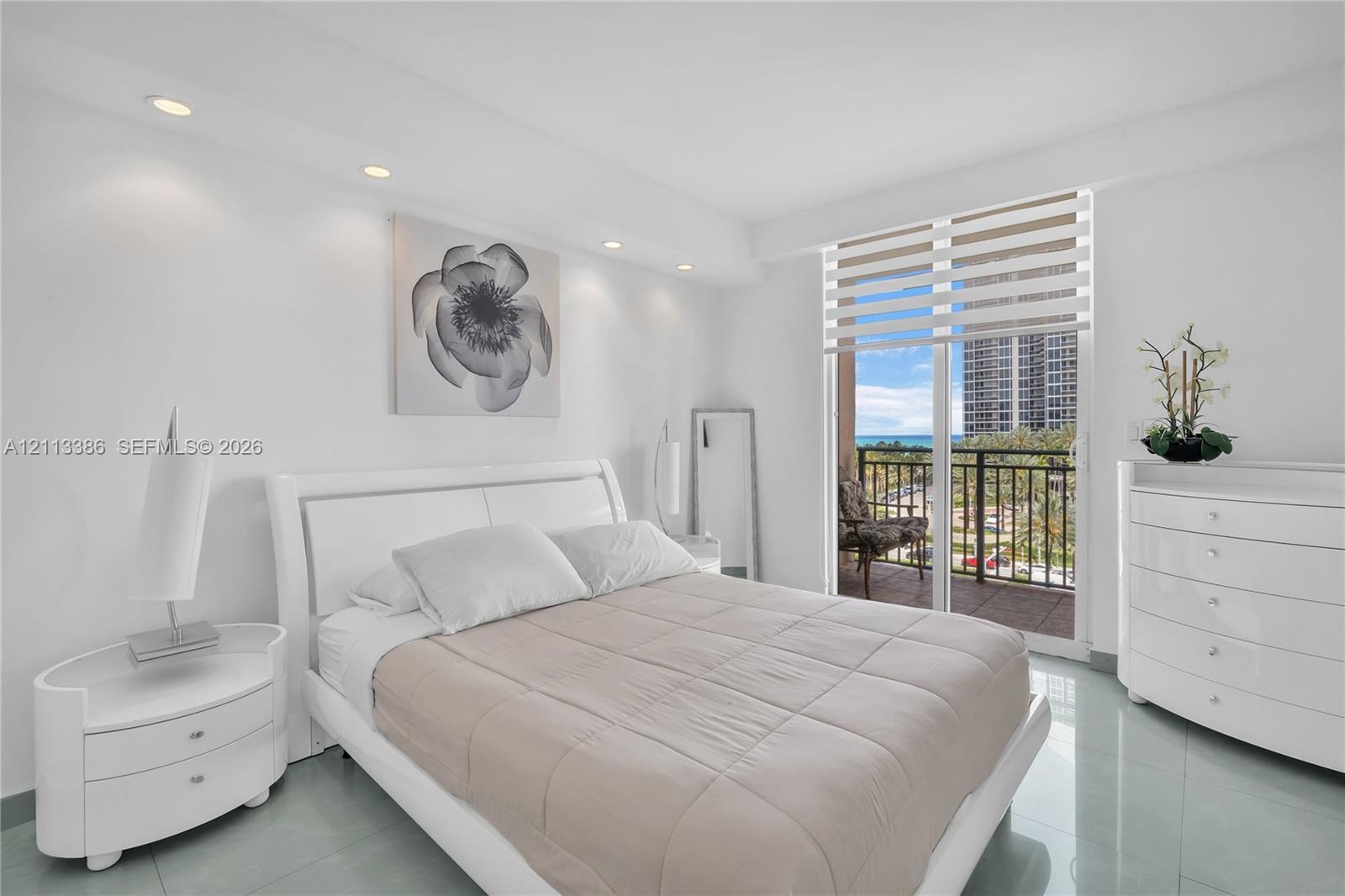Sleek tile flooring, recessed ceiling lighting, and sliding glass doors opening to a private balcony with an exterior railing