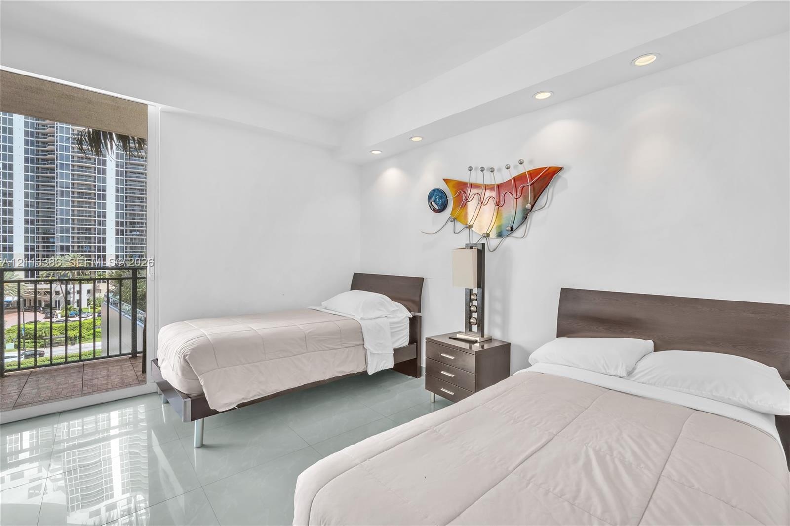 Living space with large-format tile flooring, recessed ceiling lighting, and a private balcony featuring a metal railing
