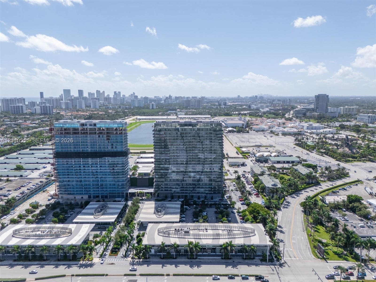 Aerial perspective of high-rise structures featuring glass curtain wall construction and expansive paved parking areas