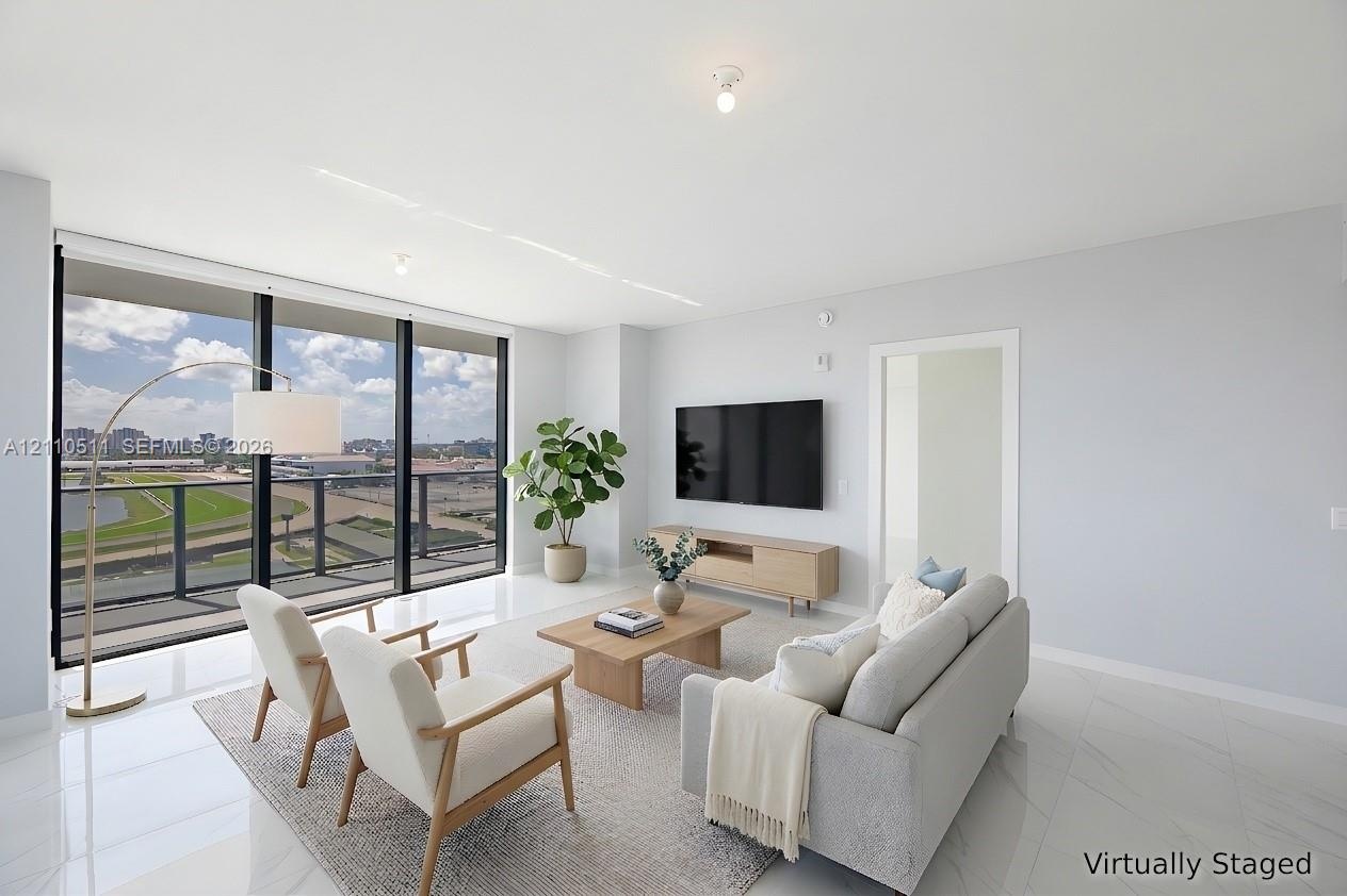 Floor-to-ceiling windows, polished tile flooring, black-framed balcony access, and neutral interior finishes