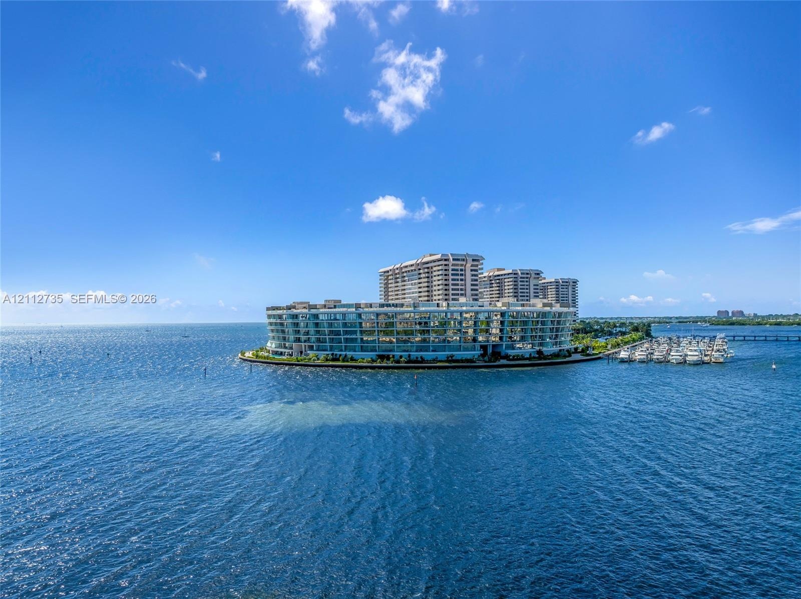 Waterfront multi-story residential structure featuring curvilinear architecture, expansive glass balconies, and private boat slips