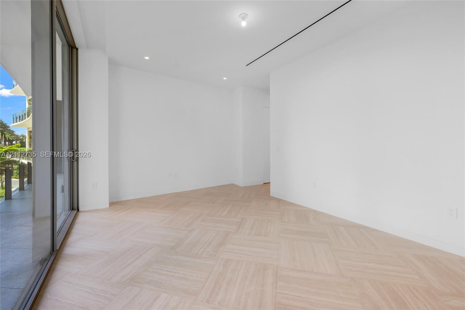 Light-filled interior featuring wood-finish flooring in a basketweave pattern, floor-to-ceiling sliding glass doors, recessed lighting, and linear cei
