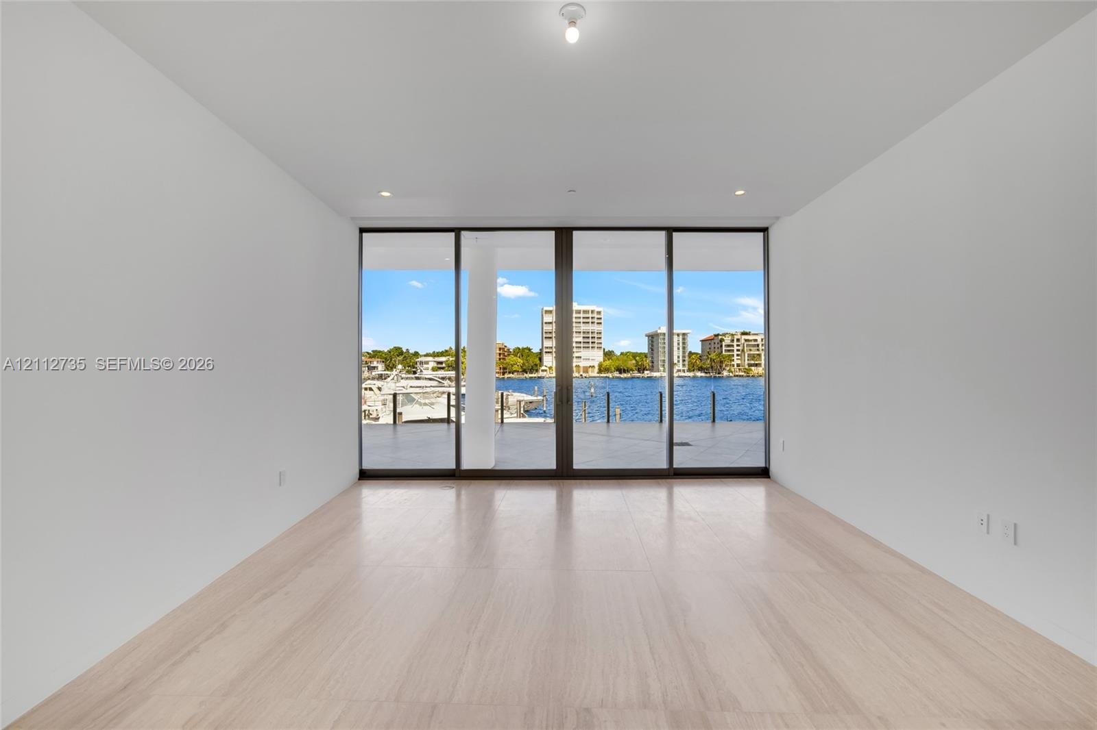 Floor-to-ceiling glass doors, neutral wood-finish flooring, recessed lighting, and outdoor terrace access