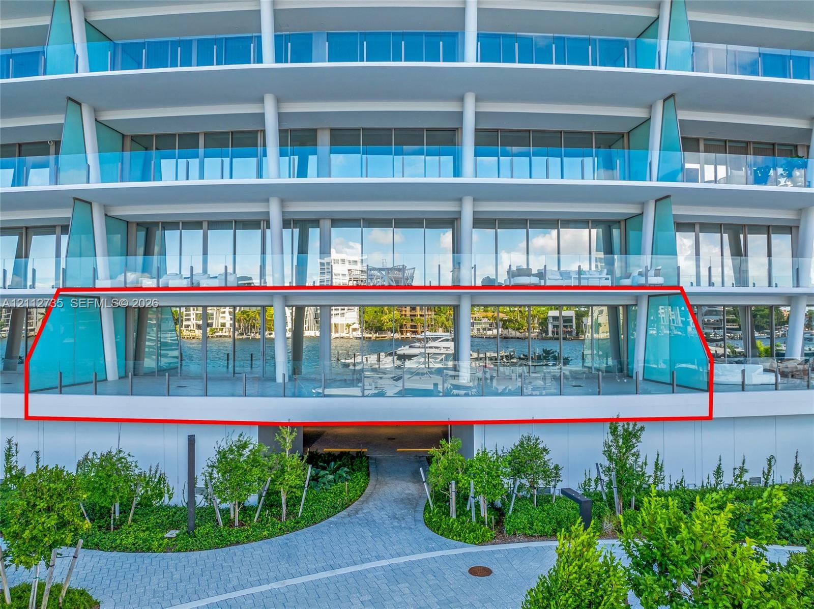Expansive private terrace featuring glass panel railings, floor-to-ceiling sliding glass walls, and unobstructed water frontage