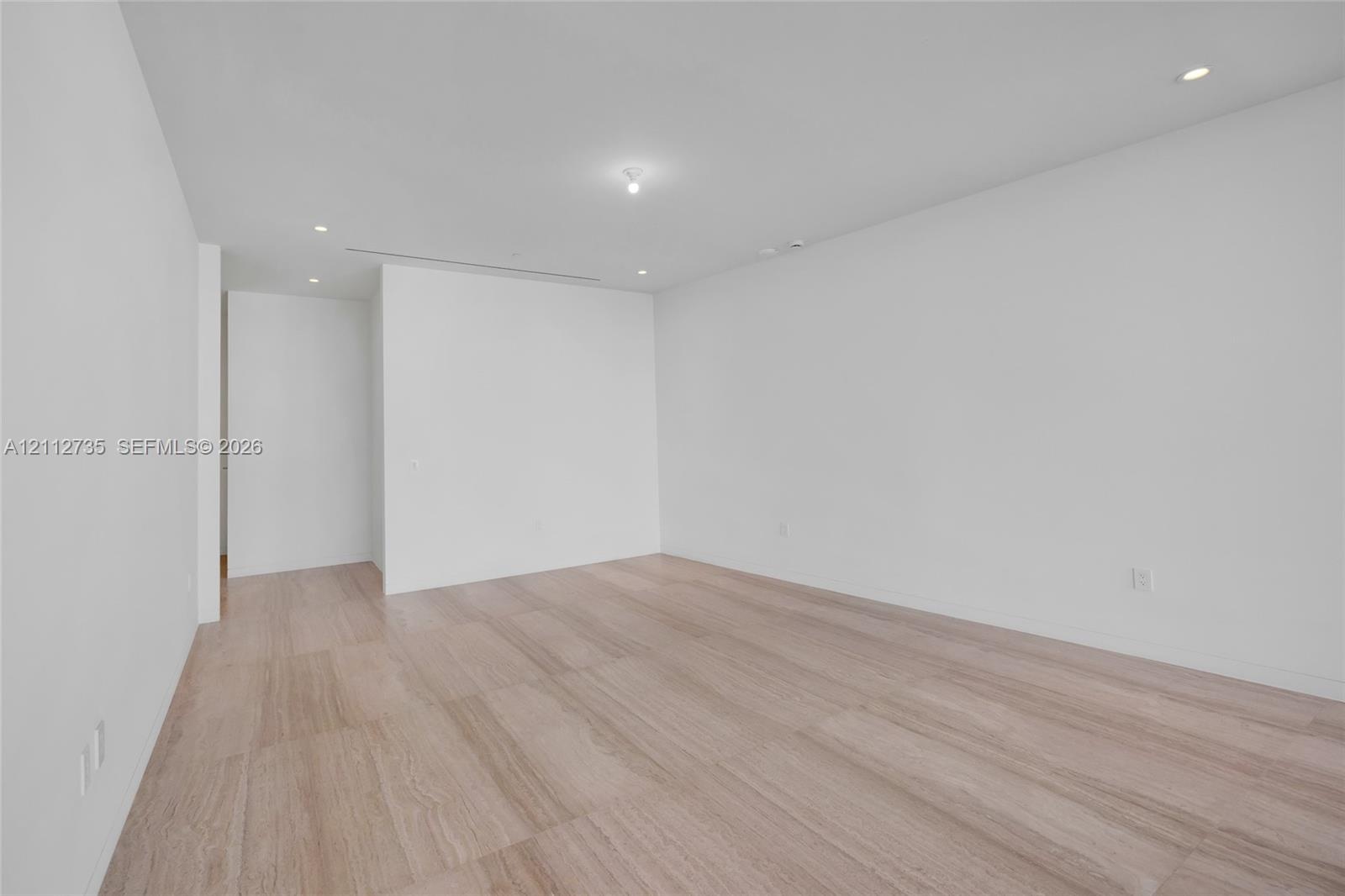 Neutral-toned interior space featuring wood-finish flooring, crisp white walls, and recessed ceiling lighting