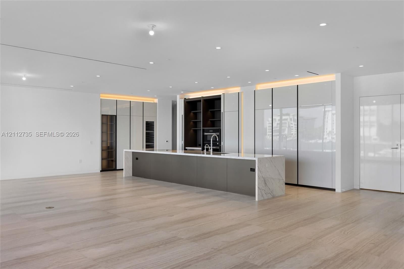 Modern kitchen featuring high-gloss cabinetry, a central island with stone surfacing, integrated appliances, recessed lighting, and wood-finish floori