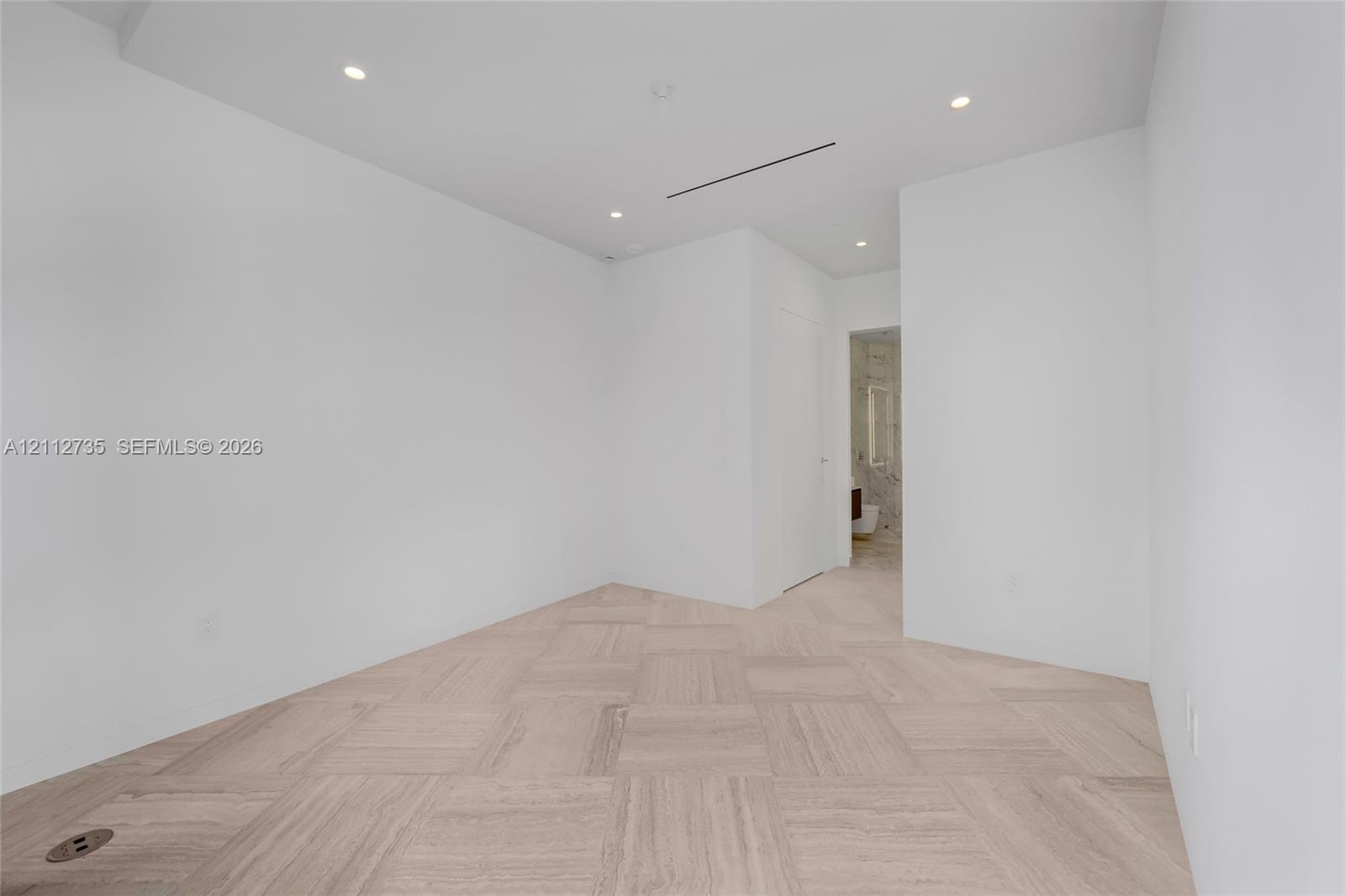 Neutral interior space featuring basket-weave pattern stone flooring, recessed ceiling lighting, and smooth-finish white walls