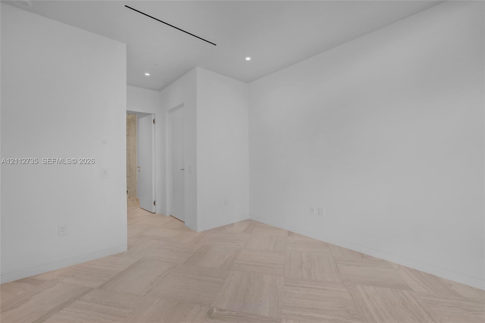 Minimalist interior featuring wood-finish parquet flooring, recessed ceiling lighting, and linear recessed ceiling detailing
