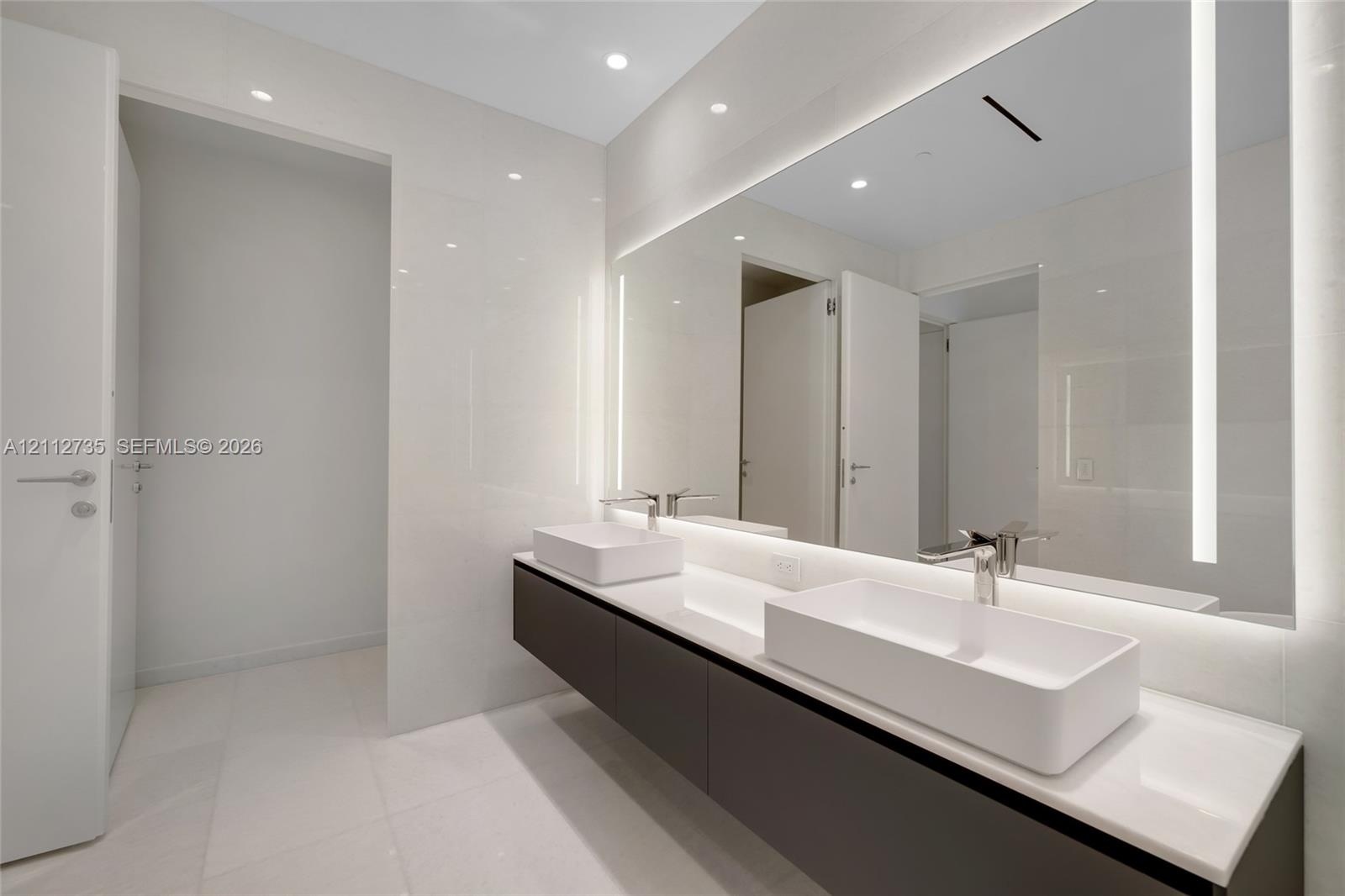 Floating dual-sink vanity featuring square vessel basins, quartz countertop, large wall-to-wall integrated LED vanity mirror, and polished chrome fixt
