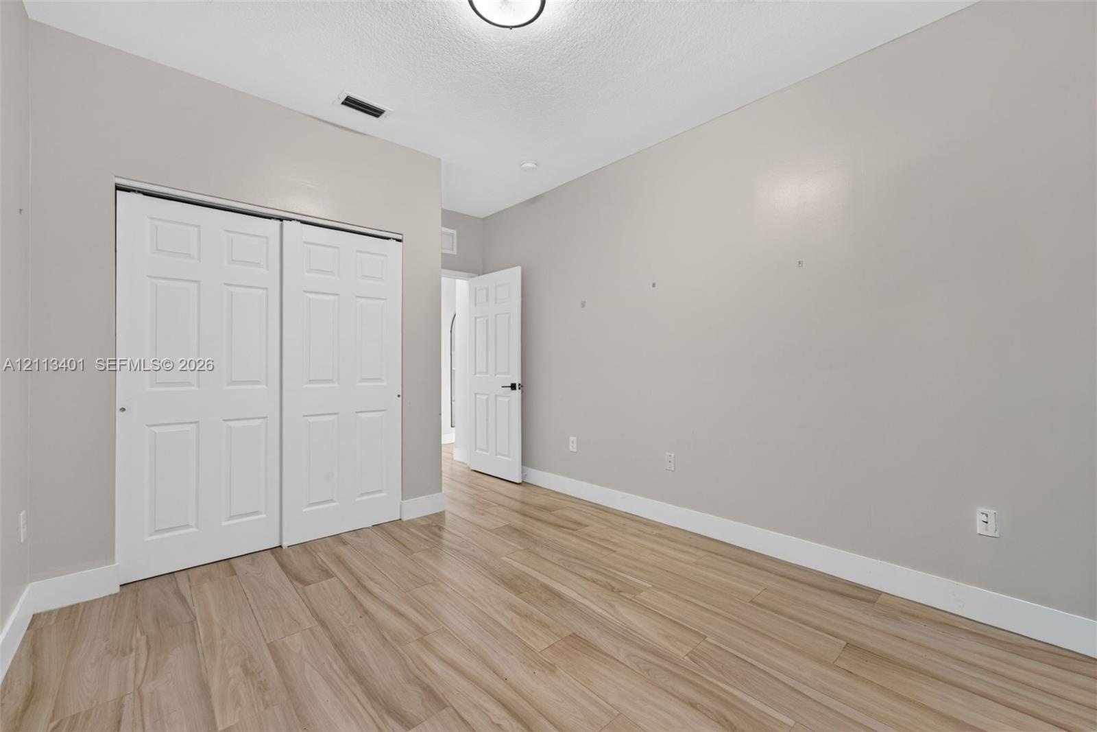 Room featuring wood-finish flooring, neutral wall paint, and a sliding-door closet