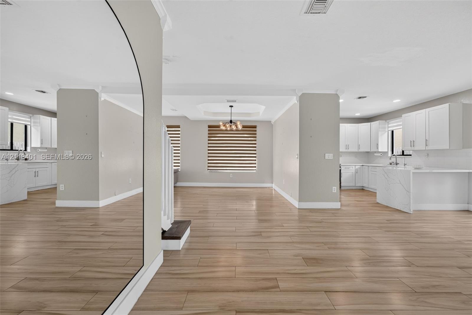Open-concept interior featuring wood-finish tile flooring, white cabinetry with stone-finish waterfall countertops, recessed lighting, and a modern ti