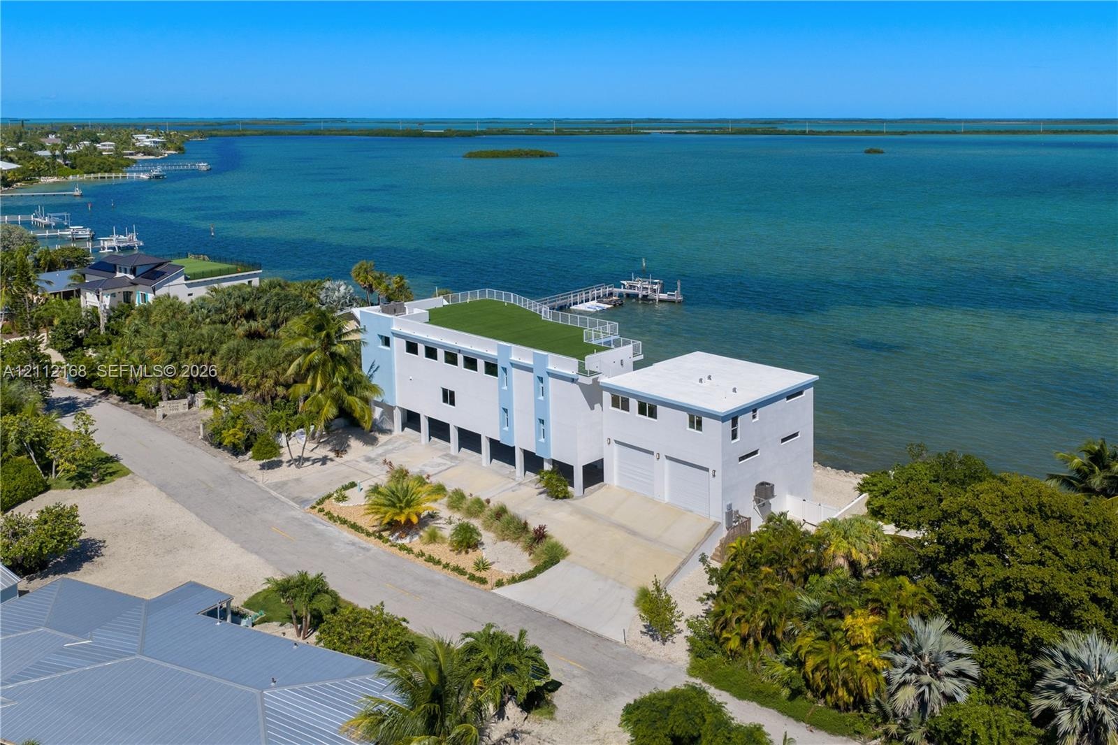 Waterfront property featuring a private dock, expansive rooftop terrace, two-car garage, and established tropical landscaping