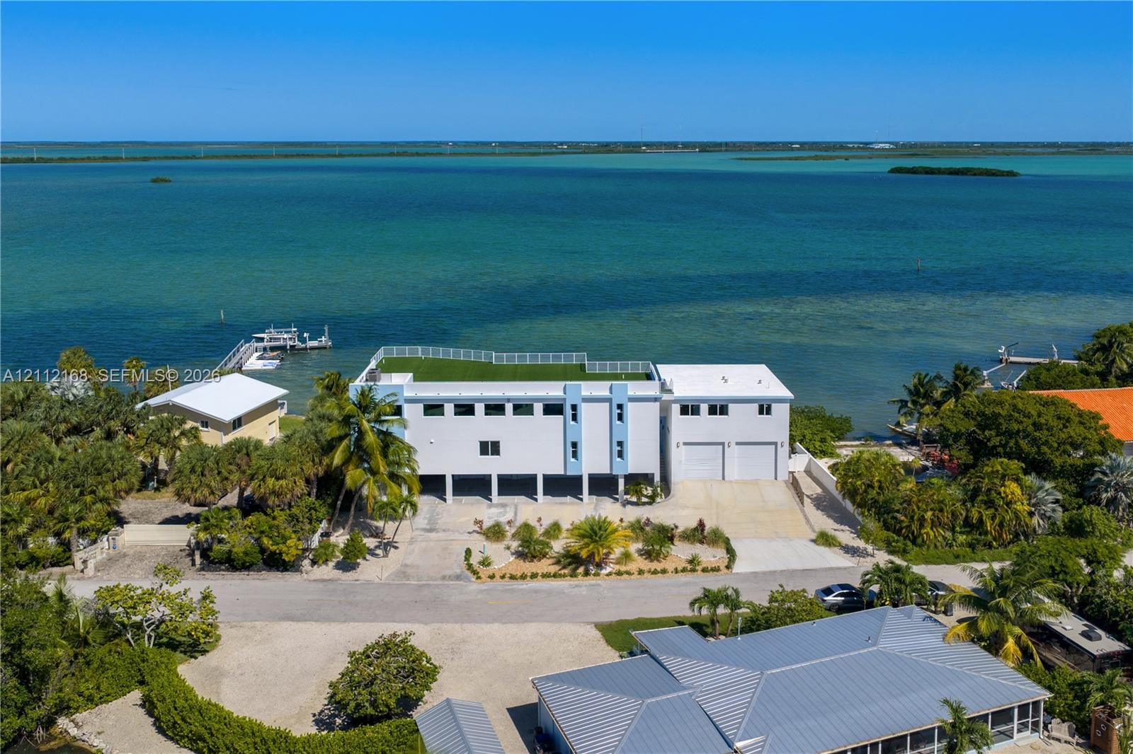 Waterfront property featuring a rooftop terrace, multi-level construction, attached two-car garage, and private dock