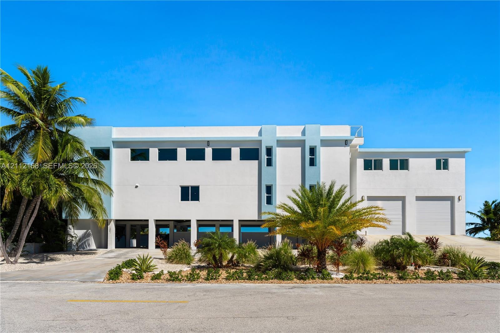 Contemporary multi-level exterior featuring white stucco finish, dual garage bays, expansive windows, and integrated ground-level parking