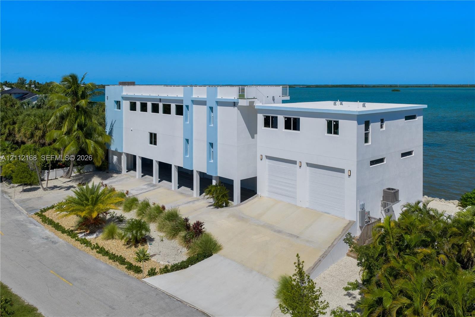 Contemporary multi-level waterfront residence featuring a concrete exterior, dual-car garage, and roof deck