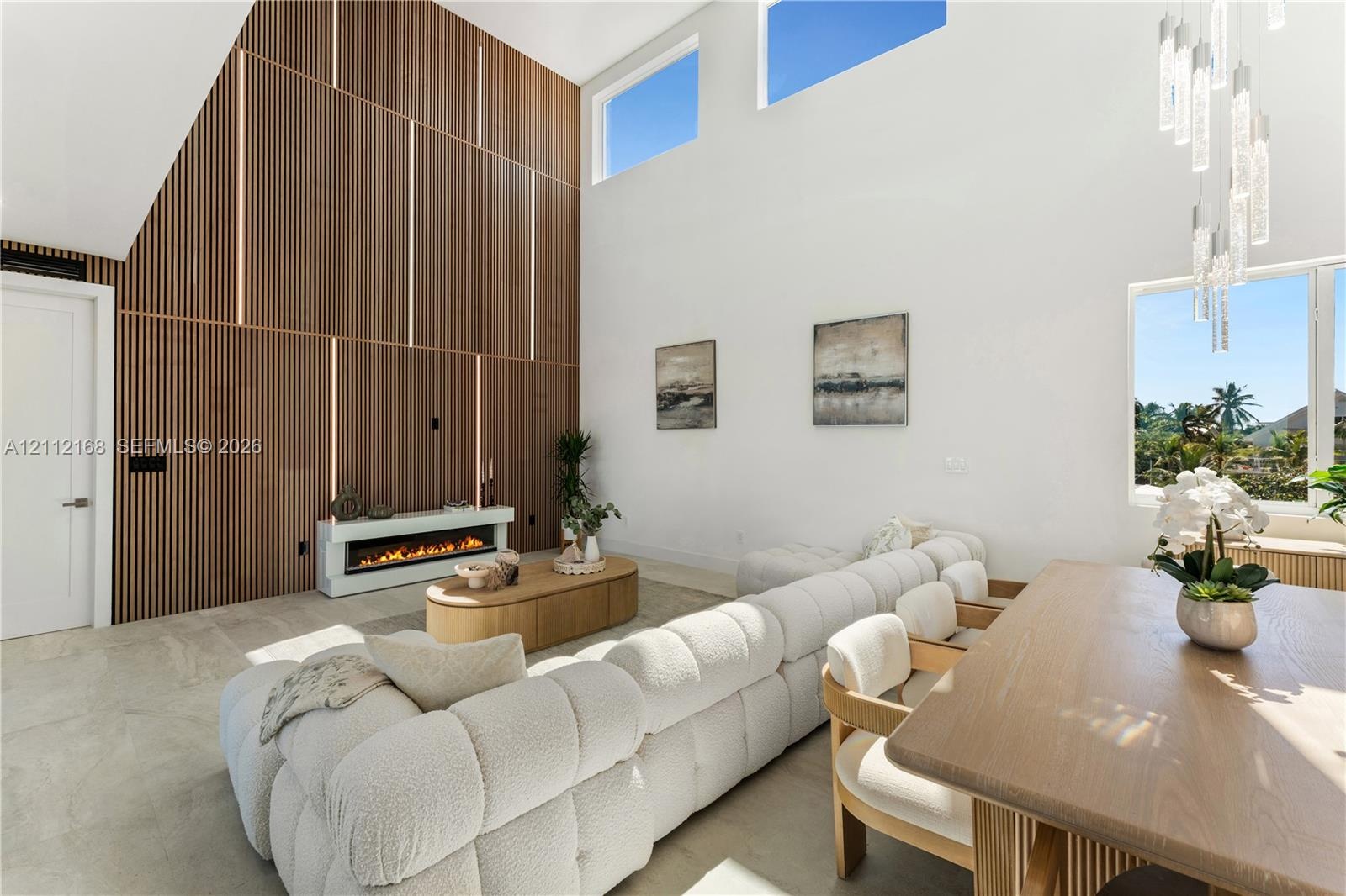 Double-height ceilings with clerestory windows, vertical slat wood-finish accent wall with integrated lighting, built-in linear electric fireplace, st